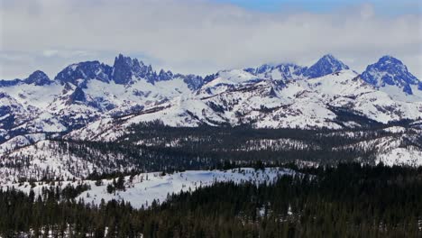 banner peak volcanic ridge minaret summit pass mammoth mountains vista parallax winter aerial drone california group jagged towering snow covered peaks sunny blue sky inyo forest sierras pct upwards