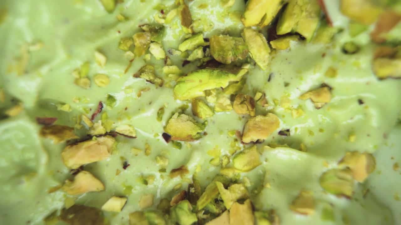 Delicious creamy pistachio ice cream captured in a top-down macro shot, surrounded by raw pistachio nuts