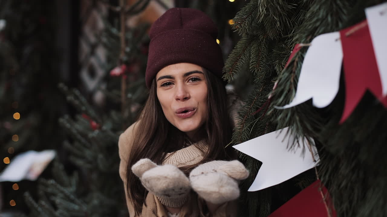Winter portrait of a woman in a hat and mittens near a Christmas tree