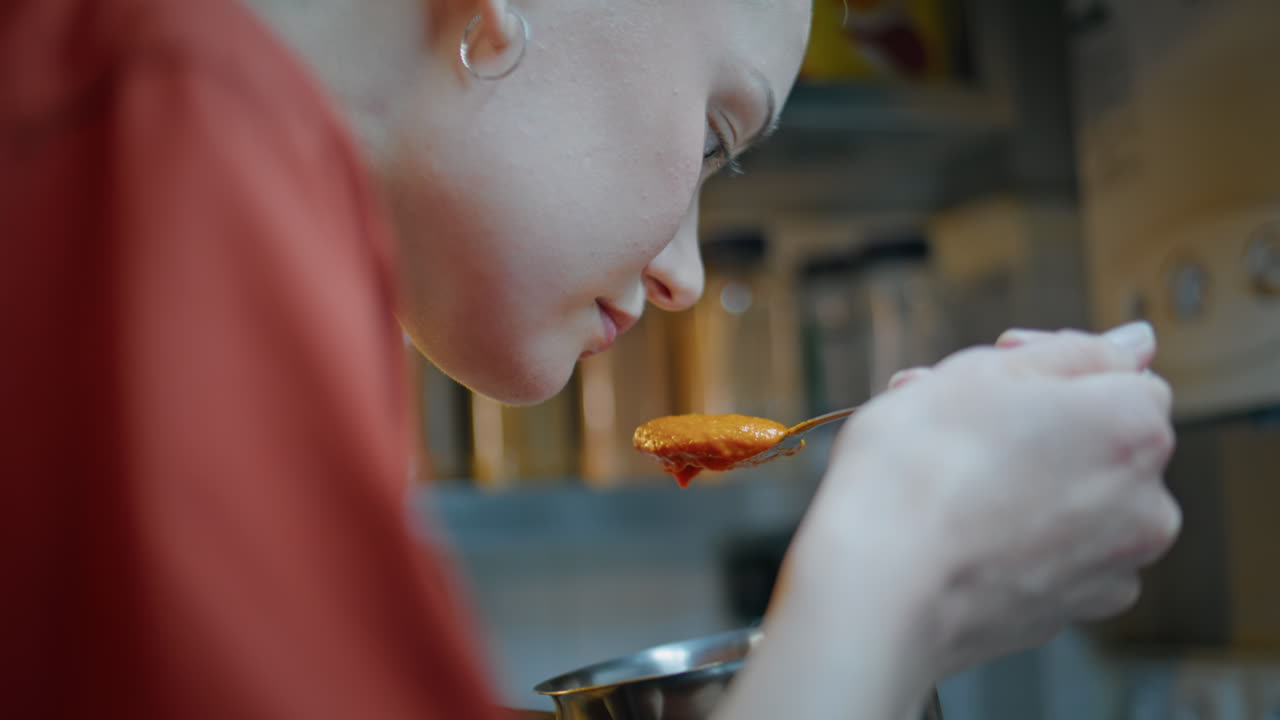 Woman cook preparing sauce in modern cuisine closeup. Focused chef sniffing