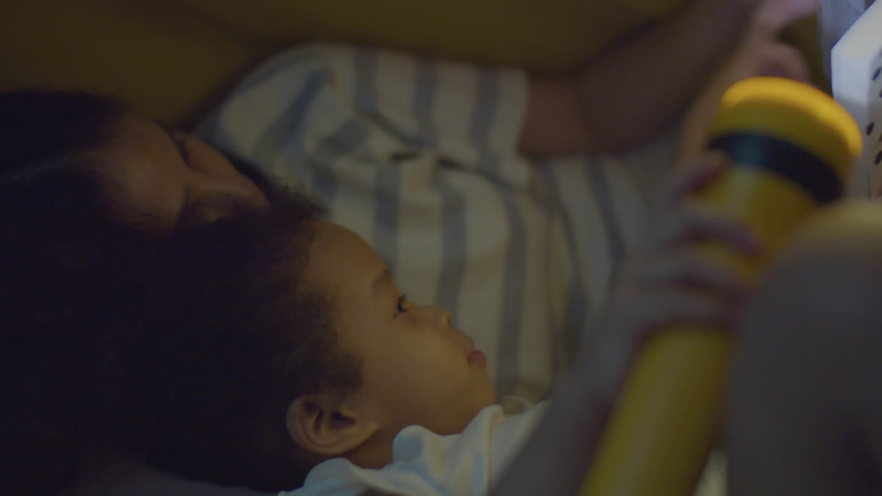 Asian Mom and Little Daughter Lying on Bed and Reading Book