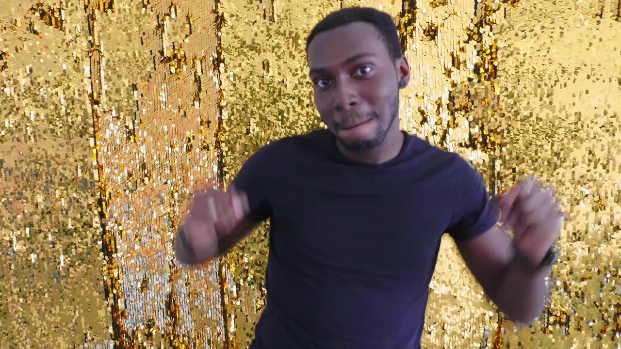 Happy Man Celebrating Against Gold Glitter Backdrop
