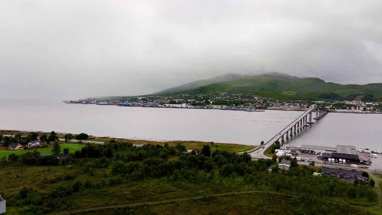 Aerial view of Sortland in Northern Norway, showcasing the long bridge, calm coastal waters, and surrounding Vesterålen landscape under soft misty weather conditions