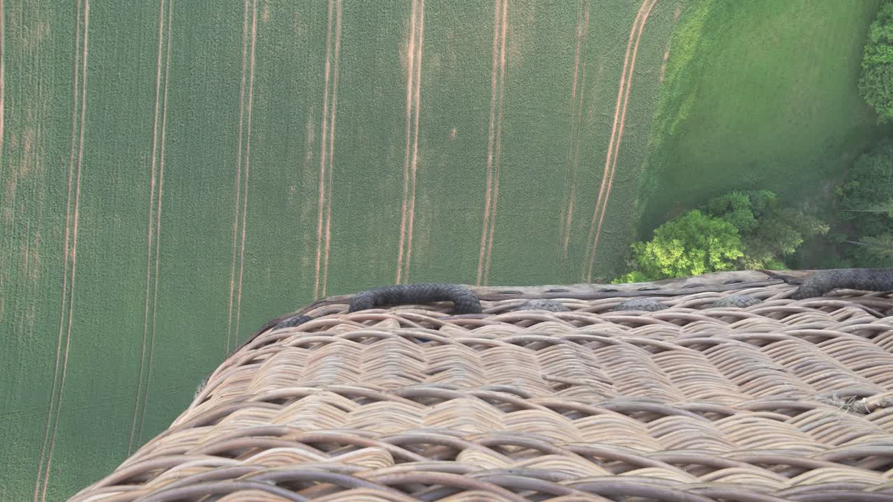 volando sobre árboles y campos en globo aerostático, vista hacia abajo con una canasta, gran toma cinematográfica con sensación del momento en el aire