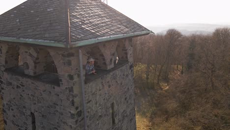 male caucasian tourist taking photos from an old brick observation tower during a sunny winter day