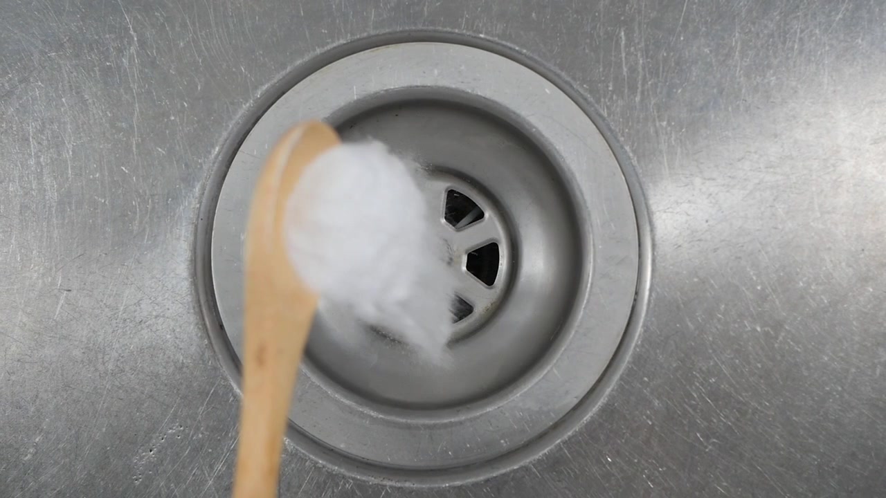 Pouring Baking Soda into a Kitchen Sink Drain