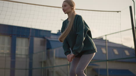 side view of lady stretching in outdoor court with building in the background, focusing on athletic posture and flexibility, emphasizing workout, health, and urban setting