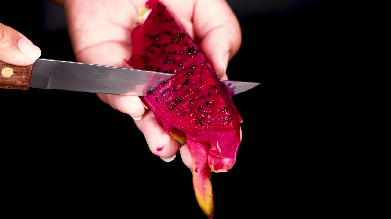 cortando a mano la fruta del dragón con un cuchillo