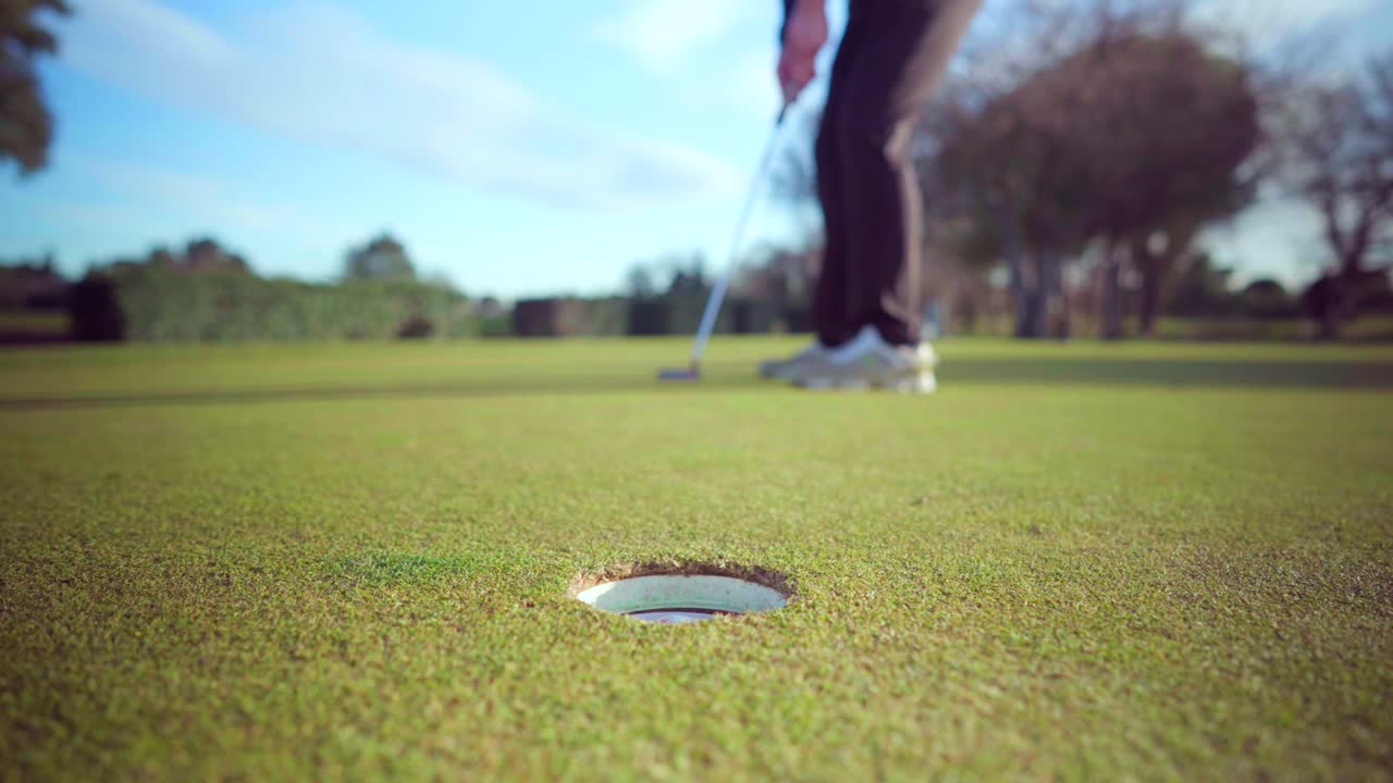 tiro exitoso de un golfista en el green de un campo de golf en un día soleado, primer plano en el hoyo