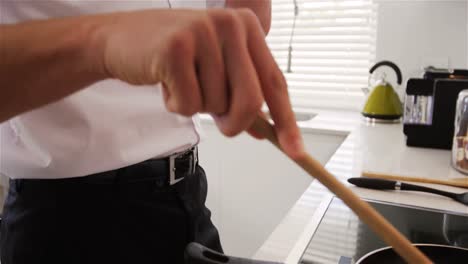 Man-talking-on-mobile-phone-while-preparing-a-food-in-kitchen