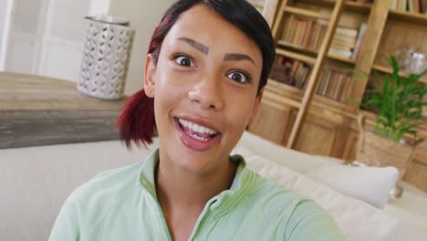 happy biracial teenager girl sitting on sofa and having video call, in slow motion