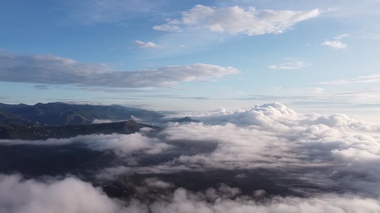 Aerial drone shot showing dramatic sunset above thick cloud layer with warm golden light and expansive sky, creating peaceful atmosphere and scenic natural landscape