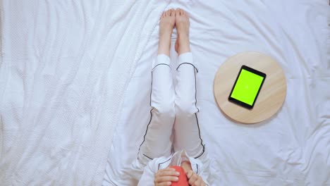 female in white pajamas holding red mug