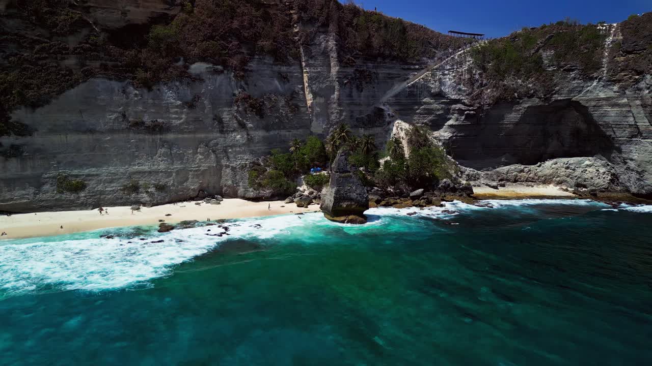 Diamond Beach in Bali, drone footage reveals a stunning view of sharp cliffs, turquoise ocean, and golden sunlight.