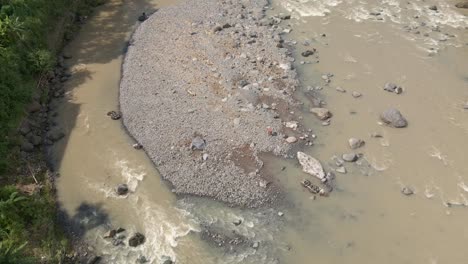 Aerial-view-of-people-on-rocky-island-in-the-middle-of-water-river-stream-mining-and-searching-for-river-stone