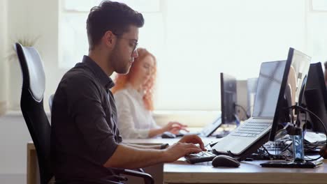 Side-view-of-young-cool-caucasian-business-team-working-at-desk-in-a-modern-office-4k