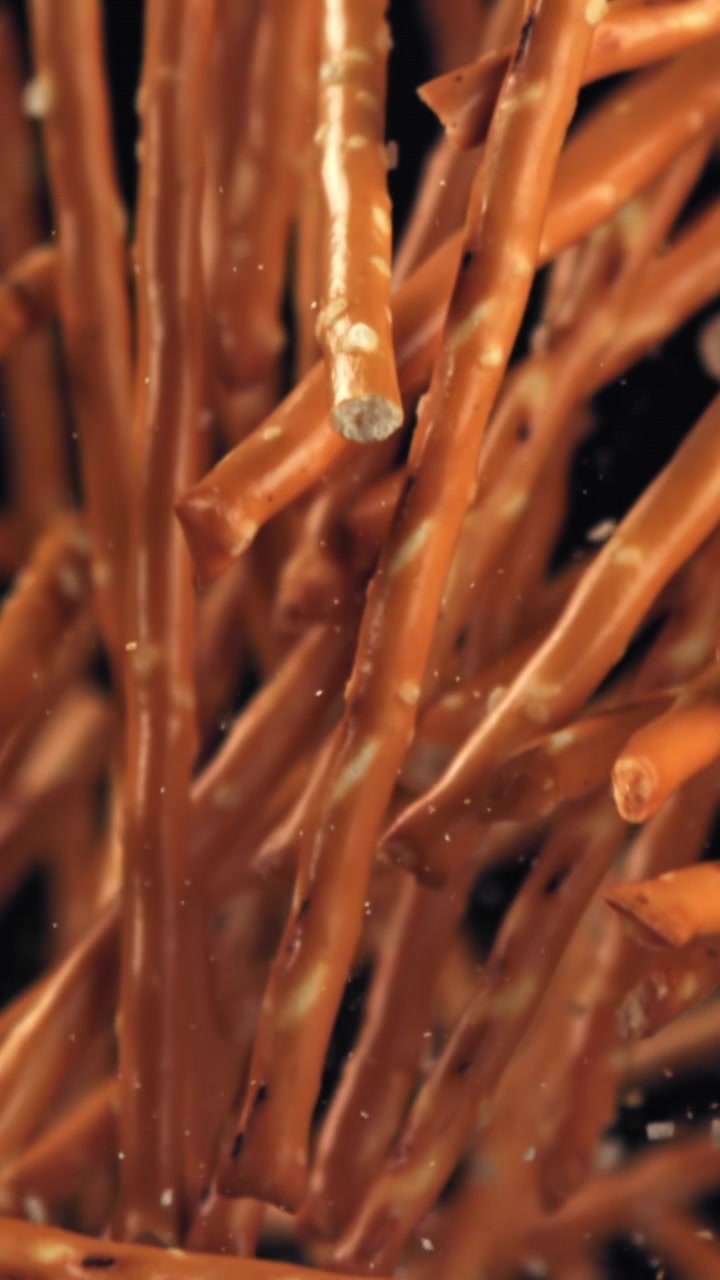 Salty Pretzel Sticks Falling in Slow Motion on Black Background