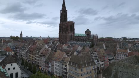 striking aerial view of strasbourg’s notre-dame cathedral towering over the colorful half-timbered houses of the historic city center under a moody sky