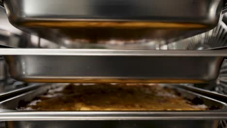 lasagna baking in an industrial oven, viewed between shiny metal shelves