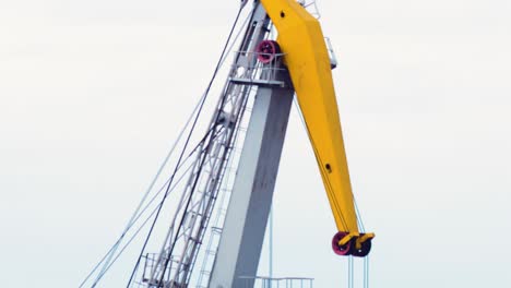 Port-cranes-loading-dry-cargo-ship-at-Port-of-Liepaja-,-overcast-spring-day,-heat-waves,-medium-shot-from-a-distance