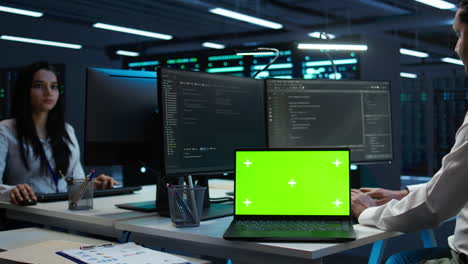 Zoom-in-on-green-screen-laptop-used-by-data-center-worker-troubleshooting-issues