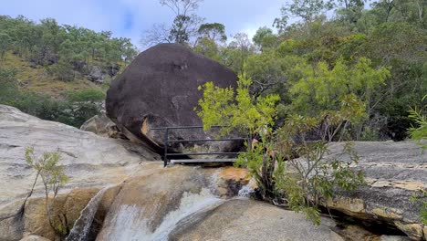 adult male wearing backpack walking across bridge beside boulder at emerald creek falls