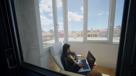 teenager working on laptop on a balcony
