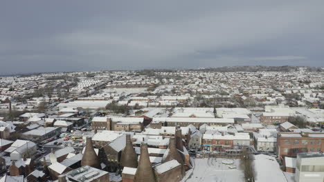 Aerial-view-of-the-famous-bottle-kilns-at-Gladstone-Pottery-Museum,-covered-in-snow-on-a-cold-winter-day-after-a-sudden-snow-blizzard,-Pottery-manufacturing,-snow-in-Stoke-on-Trent