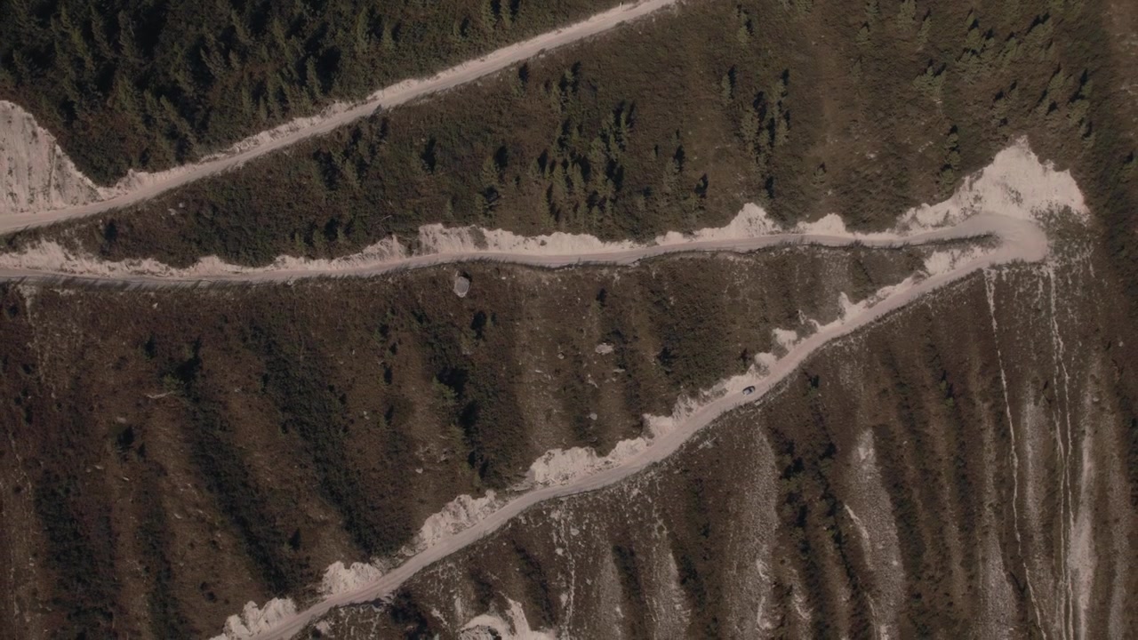 Riprese con drone della strada sterrata tortuosa e dei ripidi tornanti al Passo Katu-Yaryk sopra un aspro paesaggio vallivo nella Repubblica dell'Altai, Russia, scena di viaggio estiva.