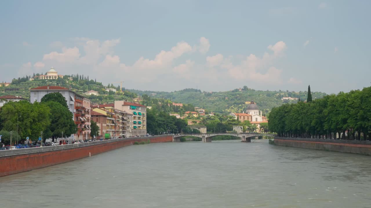 Verona, Italia - Case arroccate sopra il fiume Adige, con il Santuario della Madonna di Lourdes visibile all'orizzonte lontano - Inquadratura ampia