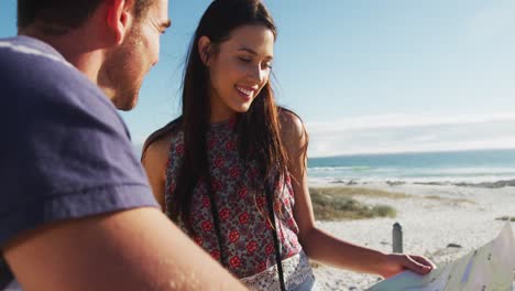 Kaukasisches-Paar-Steht-Am-Strand-Am-Meer-Und-Liest-Eine-Karte