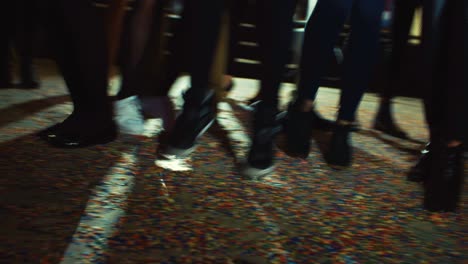 feet of people at a party with a floor full of confetti