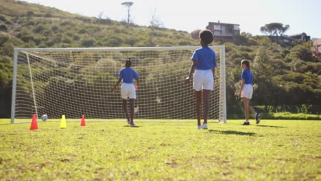 playing soccer on school field, girls in blue jerseys running towards goal