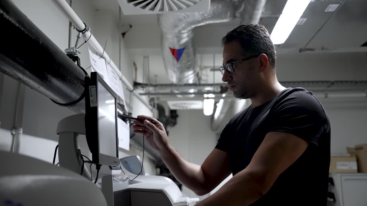 European male with athletic build and glasses working on a touchscreen device in an industrial environment