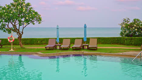 chair pool or bed pool and umbrella around swimming pool with sea background - holidays and vacation concept