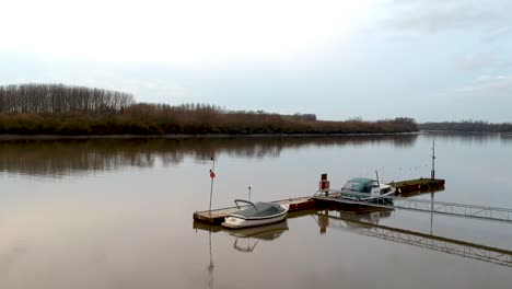 Drohne-Steigt-über-Einem-Dock-An-Einem-Fluss-Mit-Toten-Bäumen-Am-Horizont