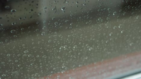 a close-up view of raindrops running down a window, capturing the moody and serene atmosphere of a rainy day.