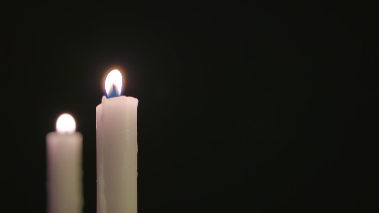 Due candele bianche accese e tremolanti al vento