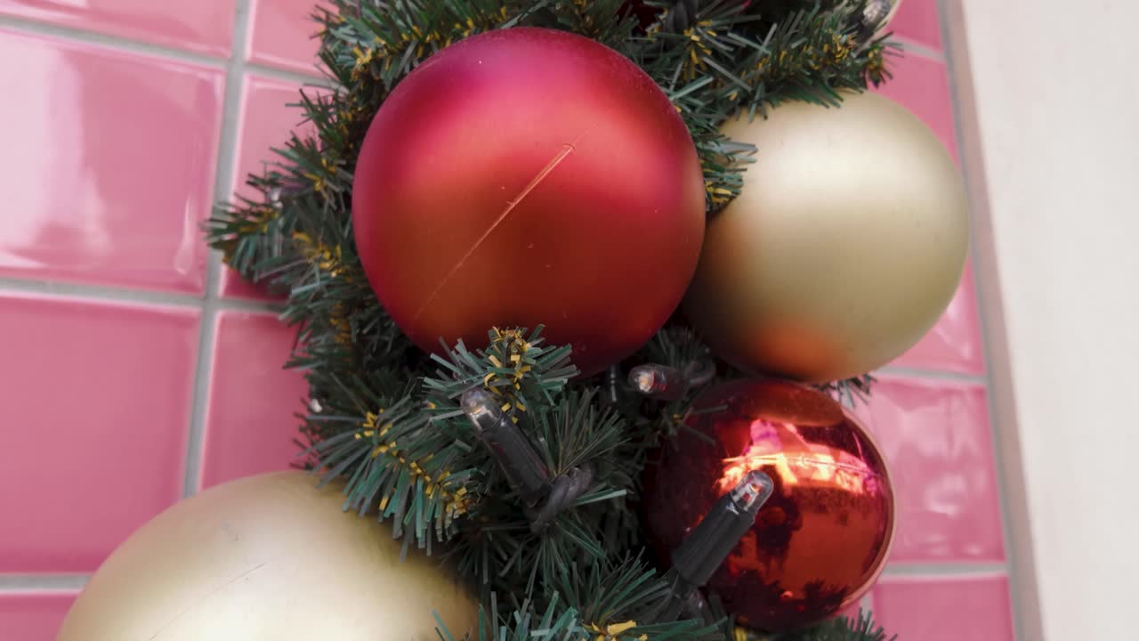 Upward movement along a decorated green branch featuring colorful Christmas ornaments