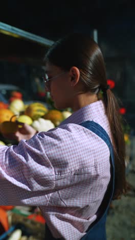 una mujer joven sosteniendo una calabaza en un mercado de agricultores