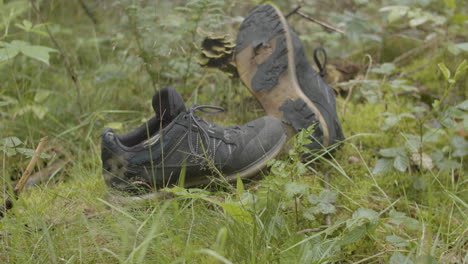 dolly out of discarded and worn hiking shoes lying in the forest