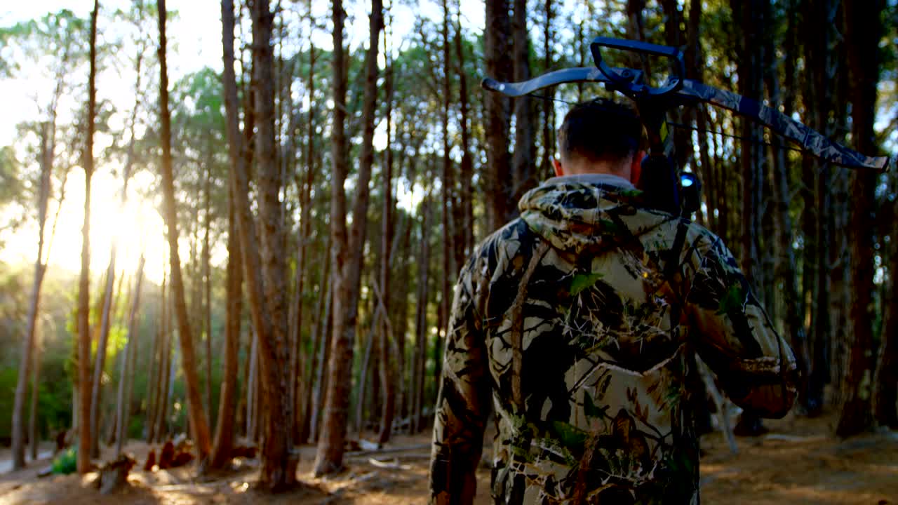 Uomo che cammina con arco e freccia nel bosco 4k