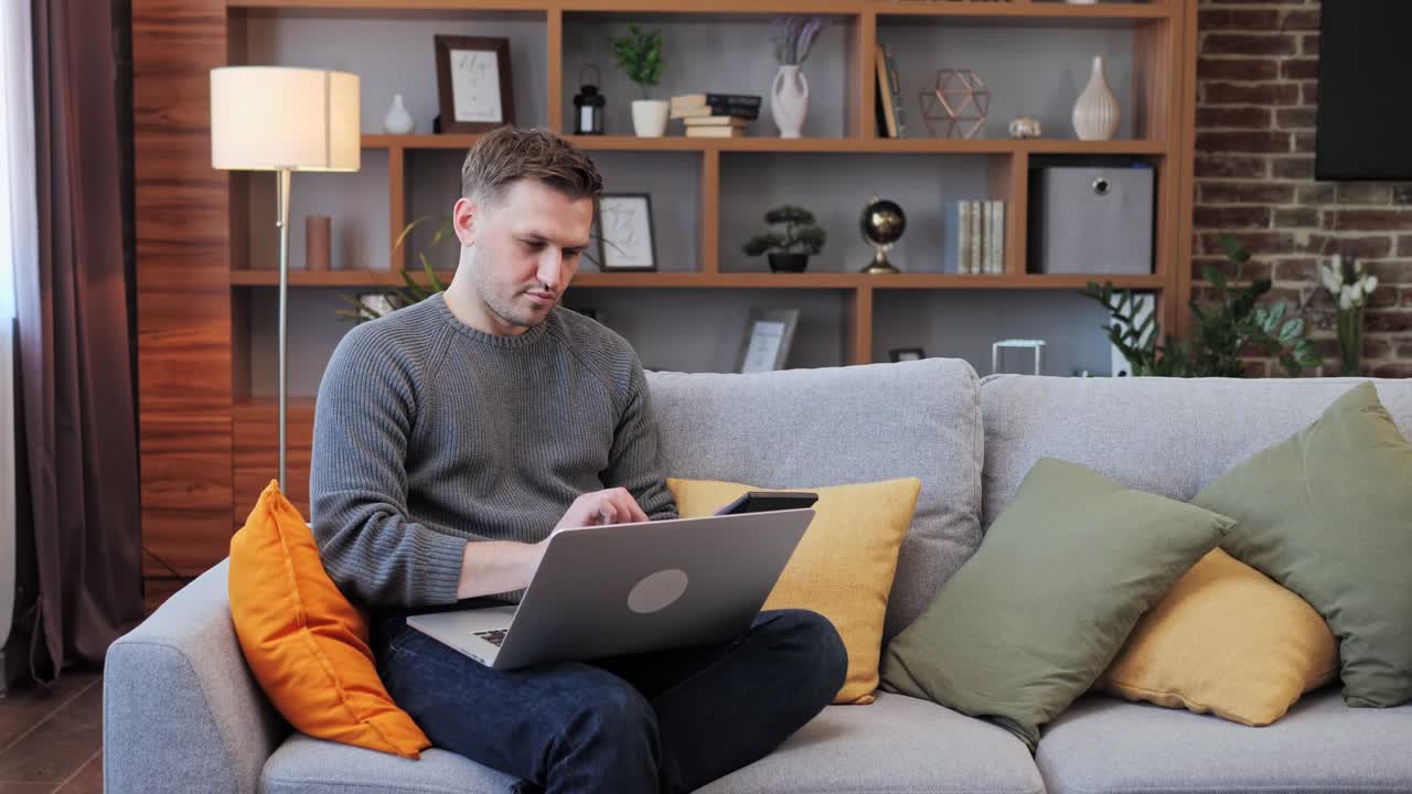 Man Working on Laptop while Sitting on Couch at home. Business, manage budget.