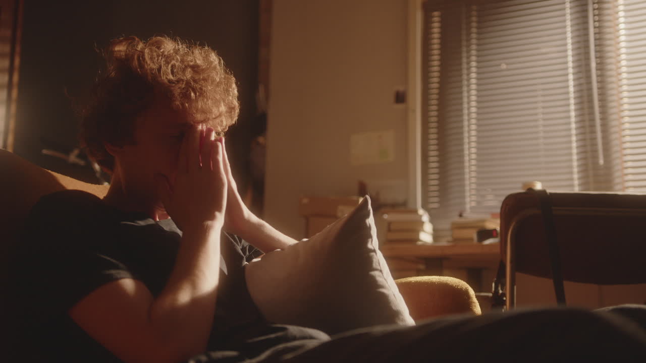 빛이 비치는 방에 앉아 우울한 생각에 빠진 불안한 남자