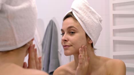 Woman-touching-her-face-and-looking-in-the-mirror-after-shower