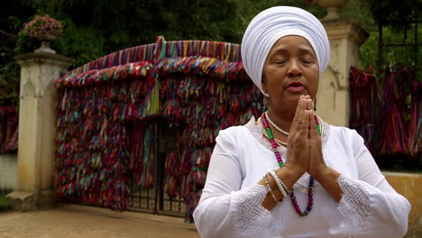 woman praying at a ribbon-adorned spiritual gate