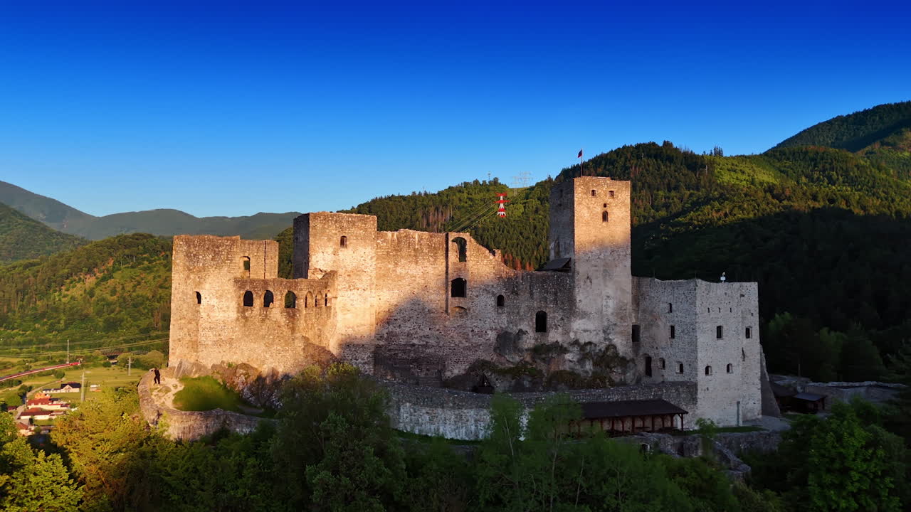 Historic castle ruins in a green valley. Ancient castle ruins rise amid lush hills under a blue sky, showcasing stunning historical architecture