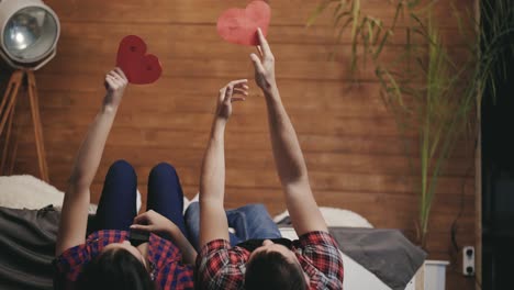 enamored man and woman are throwing down hearts handmade out of their hands on the bed together on valentine's day