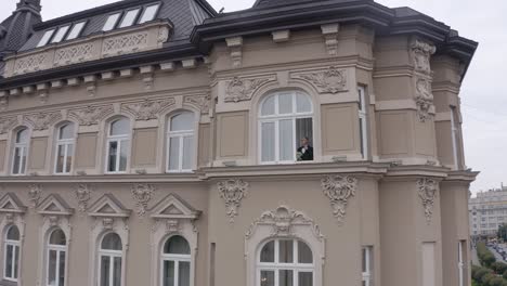 a man looks out of a window in a grand building