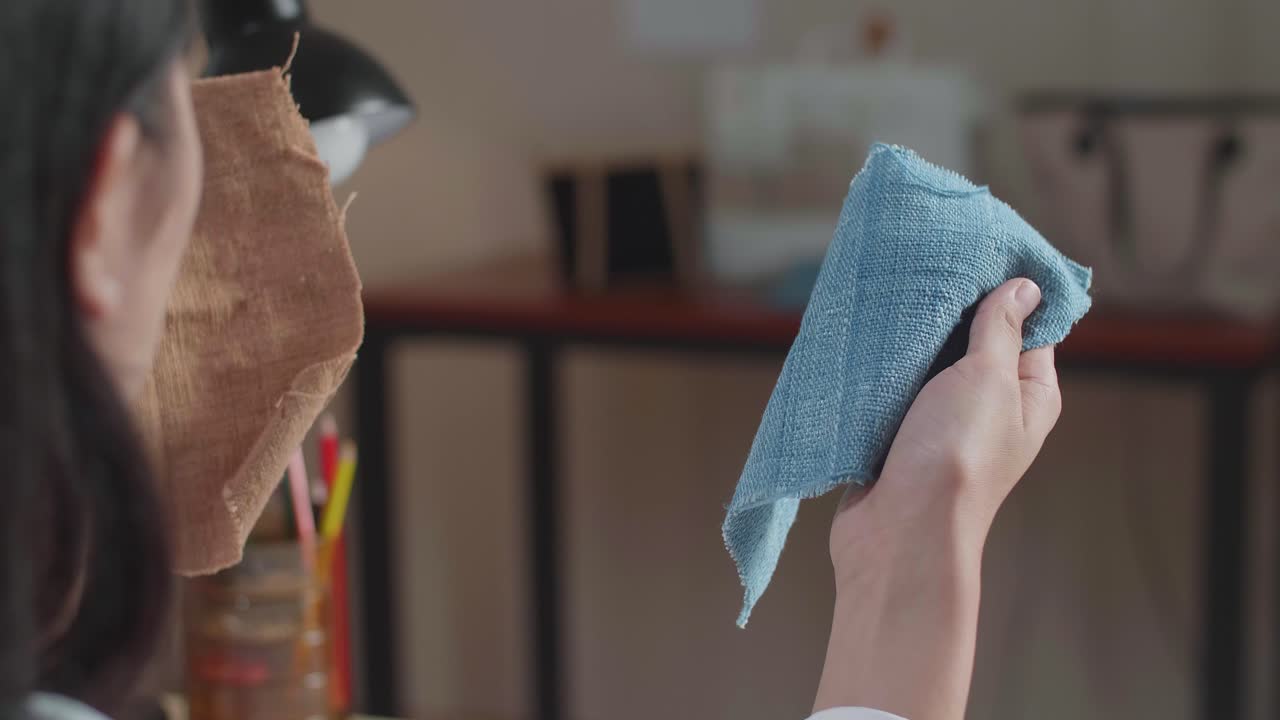 손에 든 직물을 바라보는 아시아 여성 디자이너의 클로즈업